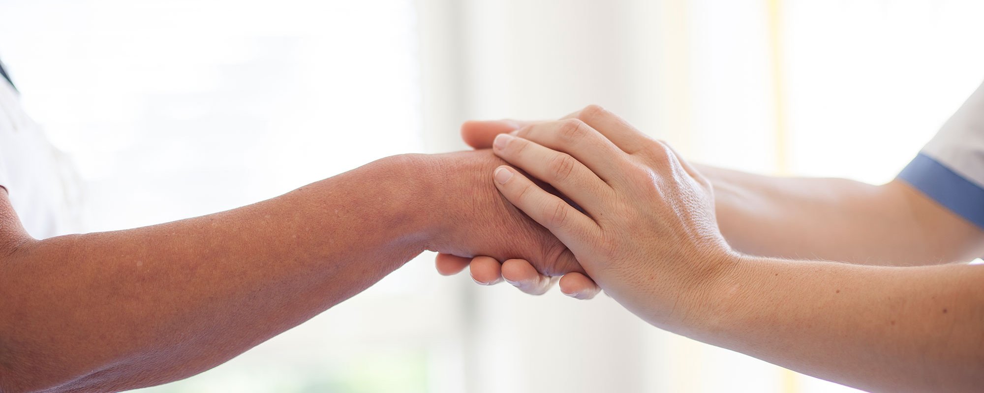 Eine Pflegerin hält die Hand eines Patienten